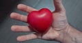 man holds a red heart and squeezes it, concept of heart prevention and care day and love and