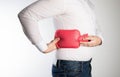 A man holds a red heating pad with water near the side of his back. The concept of treatment of sprains, hypothermia of