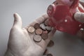 The man holds a red piggy bank and shakes out euro coins into his palm. Gloomy scene. The concept of finding money, crisis,