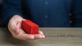 A man holds a red shipping containers in his hand. Cost savings due to bulk purchases or shared shipping expenses. Retailers and