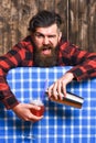Man holds shaker on plaid tablecloth background.