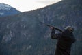 A man holds a shotgun downrange ready to fire at a clay pigeon to practice his aim