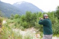 A man holds a shotgun downrange ready to fire at a clay pigeon to practice his aim