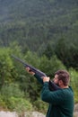 A man holds a shotgun downrange ready to fire at a clay pigeon to practice his aim in Squamish