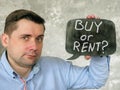 A man holds a sign saying Buy or rent. Royalty Free Stock Photo