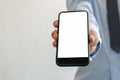 Man holds a smartphone in hand. Mobile phone mockup white screen blank Standing Against. use for marketing advertising or Royalty Free Stock Photo