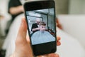 Man holds smartphone with open camera, shoots young man cuts hair in barber shop in barber shop. Smartphone takes a photo of a