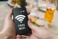 Man holds smartphone and is using free wifi in restaurant