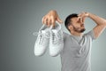 A man holds sneakers in his hands. Nasty smell. Stink legs, fungus on the legs Royalty Free Stock Photo