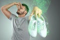 A man holds sneakers in his hands. Nasty smell. Stink legs, fungus on the legs