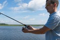 Man holds spinning in his hand for fishing against the blue sky, close-up