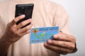 A man holds and takes a photo of his Indonesian Identity Card (KTP) using a smartphone