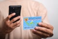 A man holds and takes a photo of his Indonesian Identity Card (KTP) using a smartphone