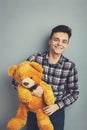 Man holds teddy bear on a light blue background, copy space. Pretty toy concept. Man hugs cute toy bear tight. Guy with happy face Royalty Free Stock Photo