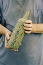 A man holds on to an old wine bottle. Hands holding a dirty glas Royalty Free Stock Photo