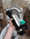 A man holds a toilet flush mechanism after repair, plumbing repair, white toilet bowl in the interior top view, toilet interior