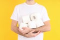 Man holds toilet paper on yellow background. Hemorrhoids concept