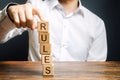 A man holds a tower of blocks with the word Rules from falling. Setting clear rule and restrictions. Leadership and discipline Royalty Free Stock Photo