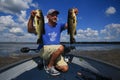 Man Holds Up Pair of Largemouth Bass While Fishing on a Boat Royalty Free Stock Photo