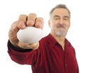 Man holds white egg in his outstretched hand.