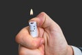 Man holds white lighter in hand and pressing it with thumb Royalty Free Stock Photo