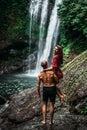 A man holds a woman in his arms at the waterfall. Couple at the waterfall, rear view. Honeymoon trip. Royalty Free Stock Photo