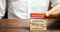 A man holds wooden blocks with the word Mediator, dispute, problem, conflict. Settlement of disputes by mediator. Dispute