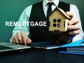 Man holds wooden home and sign remortgage