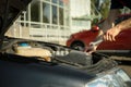 A man holds a wrench over car engine. Car inspection