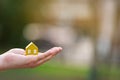 A man holds a yellow house on his hand outdoors. Real estate and affordable housing concept.