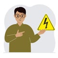 A man holds a yellow triangular warning sign with a black lightning in his hand. The concept of the danger of electric Royalty Free Stock Photo