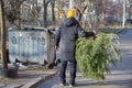 A man after the holiday throws a Christmas tree into the trash can