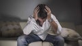 Man at home in despair - young depressed and desperate man crying on sofa couch confused and troubled suffering depression problem