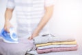 Man at home electric ironing and pile clothes variety of colors. Men ironing shirt on ironing board with steaming blue iron. Royalty Free Stock Photo