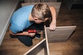 A man at home with a red screwdriver assembles a cabinet and furniture. View from above, selective focus Royalty Free Stock Photo