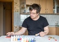 A man at home at the table. in one hand he holds a brush. the other is checked in the tablet. Royalty Free Stock Photo