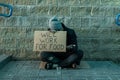 A man, homeless, a man asks for alms on the street with a sign will work for food. Concept of homeless person, addict, poverty,