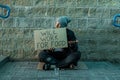 A man, homeless, a man asks for alms on the street with a sign will work for food. Concept of homeless person, addict, poverty,