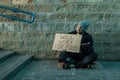 A man, homeless, a man asks for alms on the street with a sign will work for food. Concept of homeless person, addict, poverty,