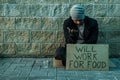 A man, homeless, a man asks for alms on the street with a sign will work for food. Concept of homeless person, addict, poverty,