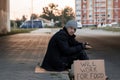 A man, homeless, a man asks for alms on the street with a sign will work for food. Concept of a homeless person, social problem,