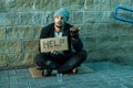 A man, homeless, a person asks for alms on the street with a Help sign. Concept of homeless person, addict, poverty, despair