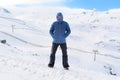 Man with hood and scarf looking frozen on snow mountain at winter landscape Royalty Free Stock Photo