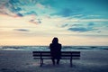 Man in hood sitting on a lonely bench on the beach Royalty Free Stock Photo