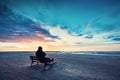 Man in hood sitting on a lonely bench on the beach Royalty Free Stock Photo