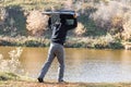 A man in a hood throws a TV into the river from a cliff