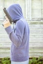 Man in hoodie holding in his hand pistol on a background the old