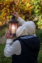 A man in a hoodie holds a glowing lantern in front of him. Concept: power outage, road search, path selection. Royalty Free Stock Photo