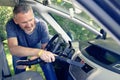 Man hoovering air vent in car