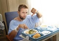 Man in hospital room eating healthy diet clinic food in upset moody face expression Royalty Free Stock Photo